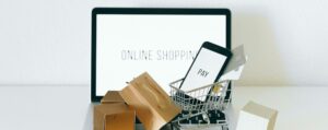 Notebook com um carrinho e caixas de compras para remeter ao tráfego pago para ecommerce