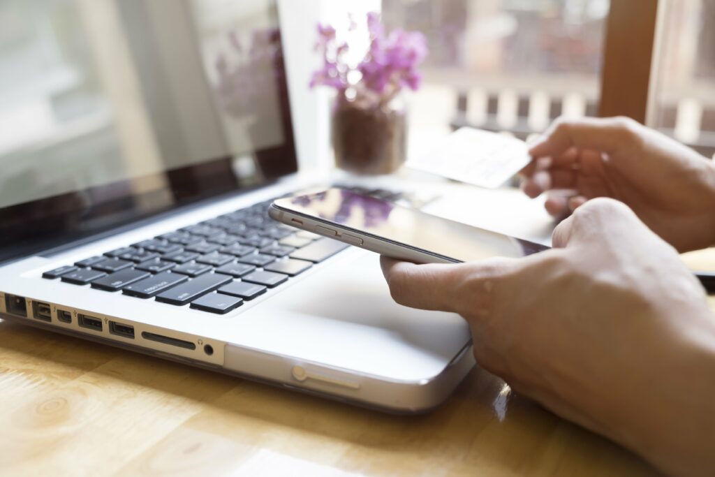 Pessoa mexendo no celular e no notebook ao mesmo tempo para acompanhar resultados do seu e-commerce 