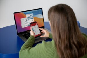 gestora de tráfego mexendo no celular e com a tela do notebook aberta