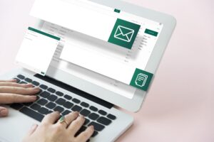Tela de notebook com página de e-mail e uma pessoa com as mãos no teclado
